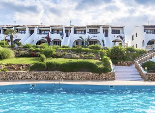 a hotel with a swimming pool in front of a building at Costa Arenal 5 in Arenal d'en Castell