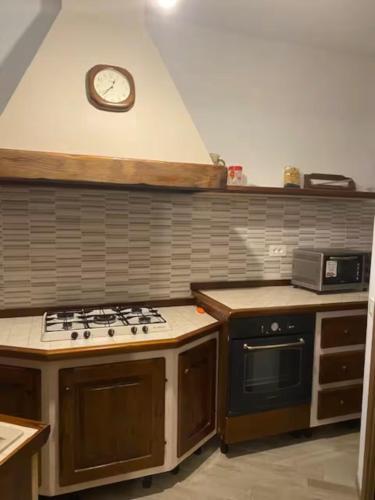 a kitchen with a stove and a clock on the wall at Il Focolare dei Sibillini in Visso