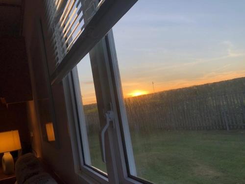 a window with a view of a field of grass at Lincolnshire Sunrise Views in Mablethorpe