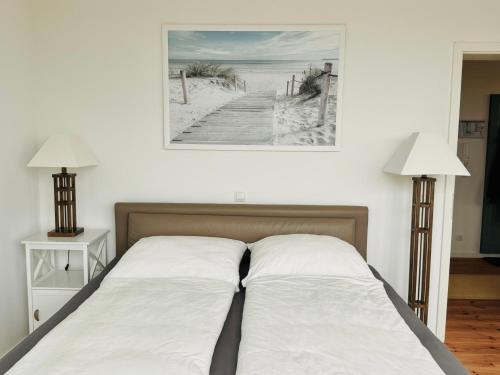 a bed with two lamps and a picture of a beach at Penthouse Am Meer Barth in Barth