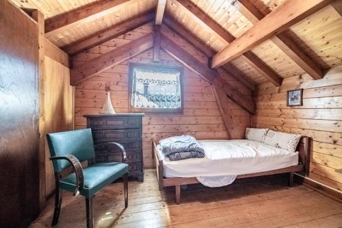 a bedroom in a wooden cabin with a bed and a chair at Chalet 6p Simple - Patchy in Verchaix