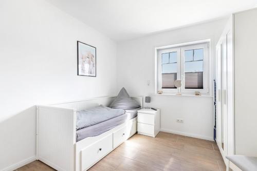 a white bedroom with a bed and a window at Ferienhus-voern-Diek in Kaiser Wilhelm Koog
