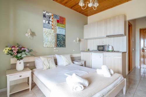 a bedroom with a white bed and a kitchen at Nontas Home 33 in Kalamitsi