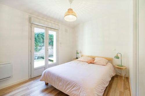 a white bedroom with a bed and a window at Maison Cosy avec Piscine in Tarnos