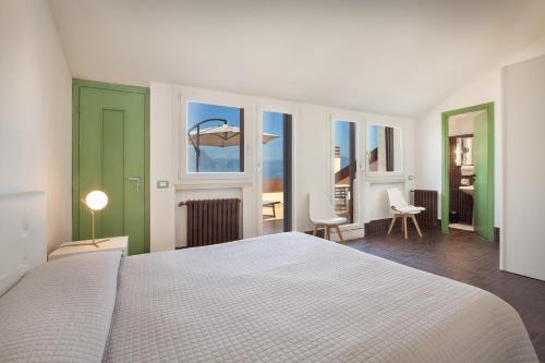 a bedroom with a white bed and a room with windows at Villa Brancolino - Fine Living in Garda