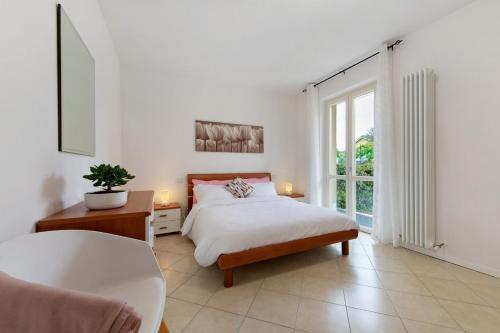 a white bedroom with a bed and a large window at Everlakegarda in Desenzano del Garda