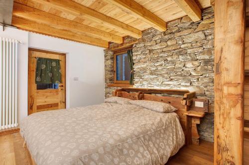 ein Schlafzimmer mit einem Bett und einer Steinwand in der Unterkunft Chalet Brenand in Rhêmes-Notre-Dame