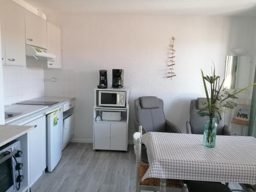 a small kitchen with a table and a microwave at Les Alisiers in Eugénie-les-Bains