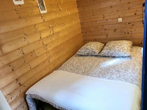 a bed in a room with a wooden wall at Maison De Plage La Grise Brèche in Pirou