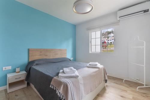 a bedroom with a bed with blue walls and a window at Giuliana Apartment in Alaior