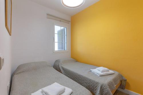 two twin beds in a room with a yellow wall at Giuliana Apartment in Alaior