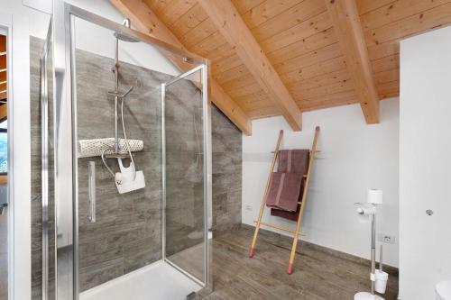 a glass shower in a bathroom with wooden ceilings at Charmingly Renovated Stone House in Cesara