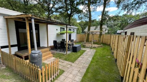 a backyard with a house and a fence at Sfeervol Chalet - Gelegen In bosrijkgebied van Drenthe - Rust en Natuur in Eext