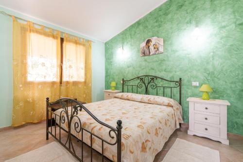 a bedroom with a bed and a green wall at Villetta Delfino in Sìnnai