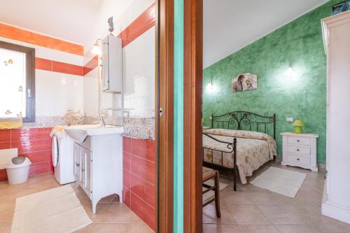 a bathroom with a sink and a bed in a room at Villetta Delfino in Sìnnai