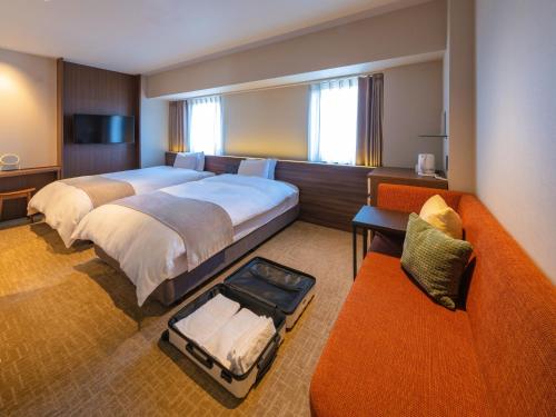a hotel room with two beds and a couch at New Osaka Hotel in Osaka