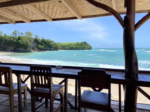 a table with chairs and a view of the ocean at Santai Surf Lodge-Balangan in Uluwatu