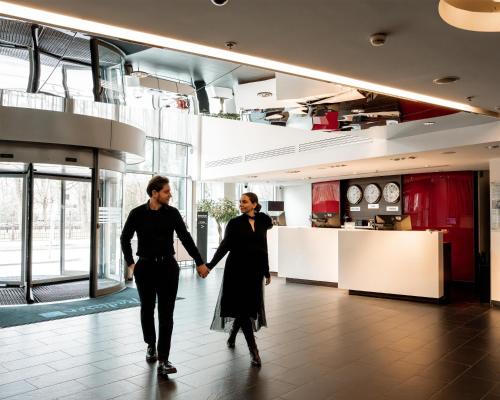 two men holding hands while walking through a lobby at Radisson Blu Elizabete Hotel, Riga in Riga
