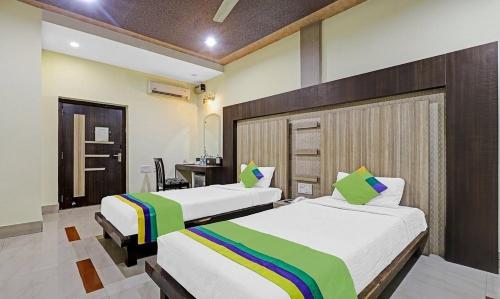 a bedroom with two beds and a desk in it at Hotel Apollo in Guwahati