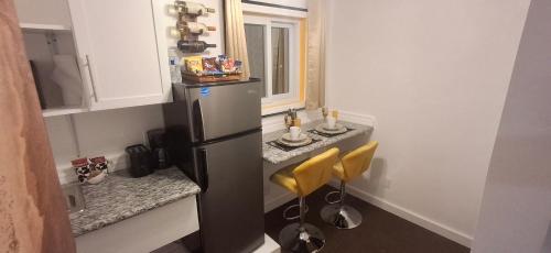 a kitchen with a refrigerator and two yellow stools at BELL At The Airport Suites - No Smoking & Adults Only - Free Airport Transportation in Nassau