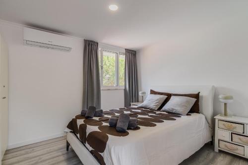 a white bedroom with a large bed and a window at Rebelsardine in Charneca