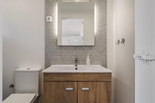 a bathroom with a sink and a toilet and a mirror at Rebelsardine in Charneca