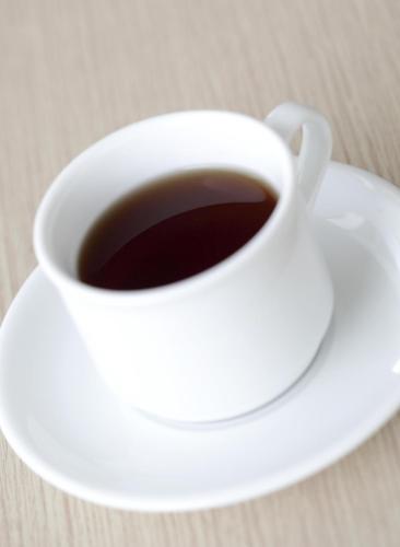 a white cup of coffee sitting on a plate at Amaris Hotel Pekanbaru in Pekanbaru