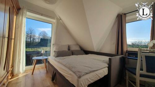 a small bedroom with a bed and a large window at Landhaus Ferien Ostsee in Sterup