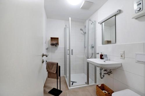 a white bathroom with a shower and a sink at Rieslingglück in Trittenheim