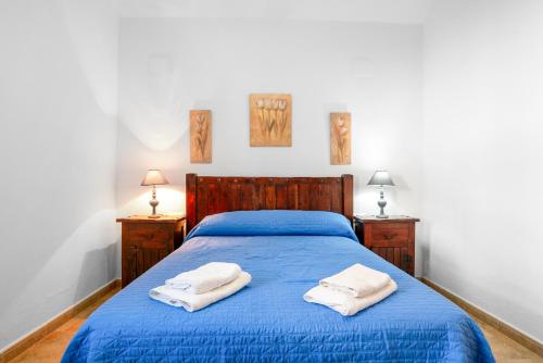 a bedroom with a blue bed with two towels on it at Chalet Villa Ariza in Cádiz