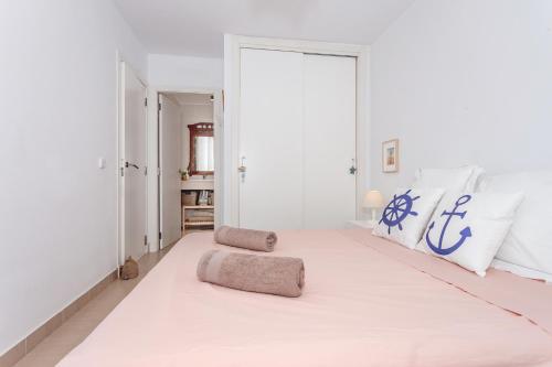 a white bedroom with a large bed with blue and white pillows at Vista Faváritx in Es Mercadal