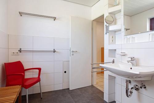 a bathroom with a red chair and a sink at Gästehaus Heinemann - Og5 in Langenargen