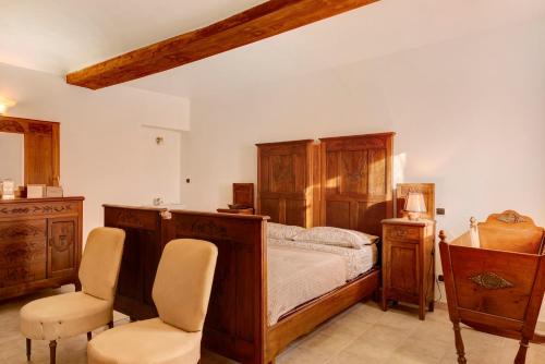 a bedroom with a wooden bed and two chairs at Tenuta Paradiso in Portacomaro