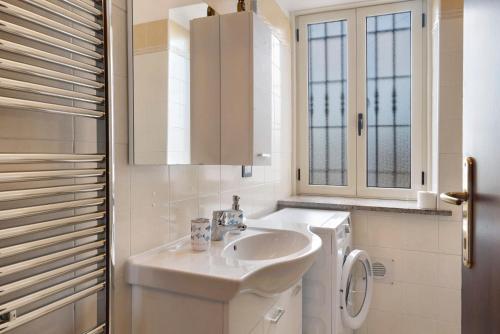 a white bathroom with a sink and a washing machine at Tenuta Paradiso in Portacomaro