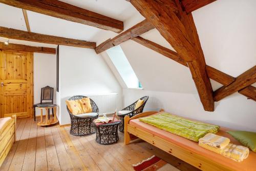 a room with a bed and chairs in a attic at Ferienwohnungen 'am Waldrand' in Bad Gottleuba