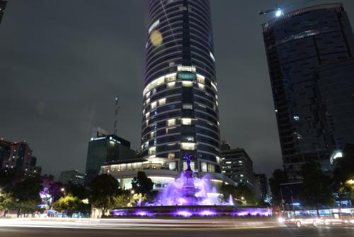 a tall building with a fountain in front of it at Apartment Cozy room in Mexico City