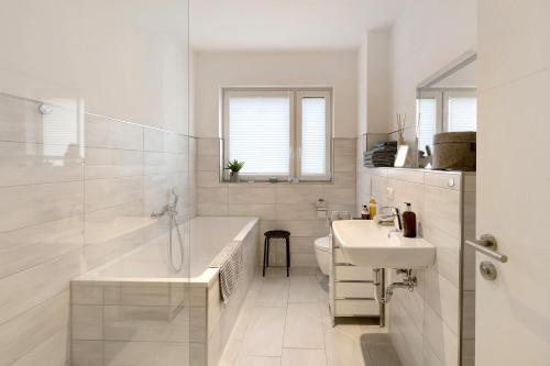 a white bathroom with a tub and a sink at Ferienwohnung 20b am Goitzsche See in Pouch
