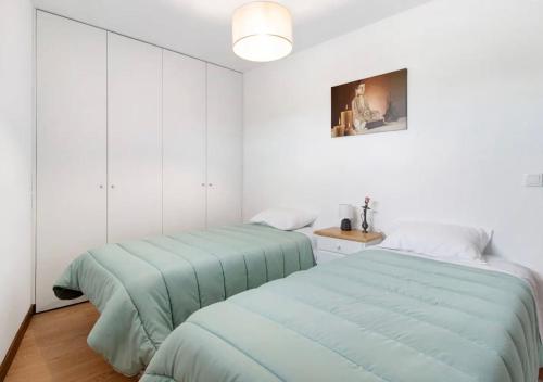 two beds in a room with white walls at Villa com 4 apartamentos in Apúlia