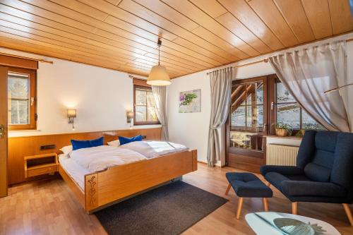 a bedroom with a bed and a couch and a chair at Gästehaus Absbachtal in Bad Rippoldsau-Schapbach