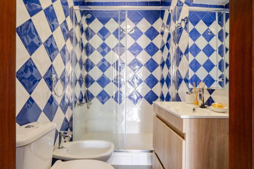 a blue and white bathroom with a toilet and a sink at Casa Do Castelo in Beja