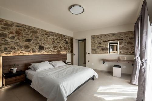 a bedroom with a large bed and a stone wall at Villa Afroditi - Sfinari in Áyios Nikólaos