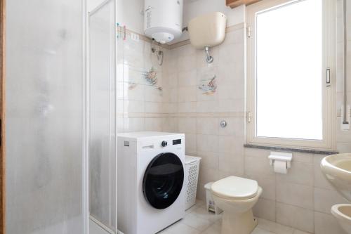 a bathroom with a toilet and a washing machine at Sa omu de sa palgia in Jerzu