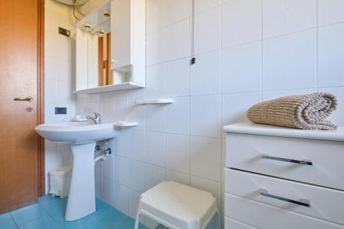 a white bathroom with a sink and a stool at Mare Etrusco Villetta D2 in Populonia