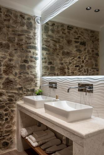 a bathroom with two sinks and a stone wall at Villa Afroditi - Sfinari in Áyios Nikólaos