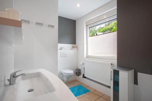 a bathroom with a sink and a toilet and a window at Fewo In Schustes in Willingen