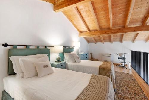 two beds in a room with wooden ceilings at Daniel Cottage - Portimão in Portimão
