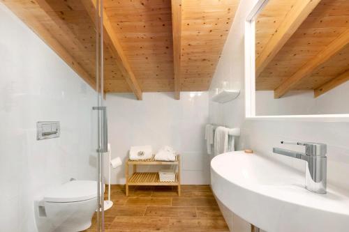 a bathroom with a sink and a toilet and wooden ceilings at Daniel Cottage - Portimão in Portimão