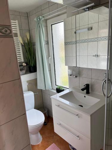 a white bathroom with a toilet and a sink at Bungalow in Gager