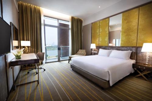 a hotel room with a bed and a desk and window at Dorsett Putrajaya in Putrajaya