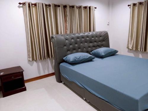 a bedroom with a blue bed with a leather headboard at บ้านกรรณิการ์ in Chiang Mai